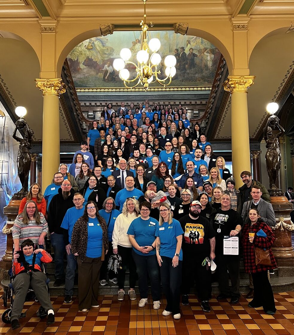 Autism Society of Iowa advocates at the State Capitol posing on the steps inside for advocacy day.